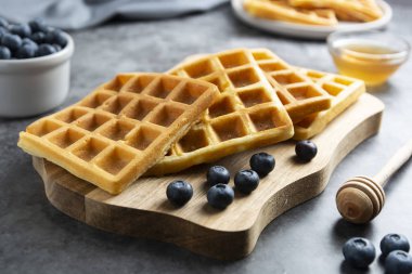 Kahvaltıda yaban mersinli ve ballı Belçika waffle 'ı. Lezzetli ev yapımı hamur işi. Koyu arkaplan.