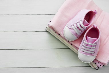 Pembe bebek ayakkabıları ve yeni doğan kıyafetleri. Annelik, eğitim ya da hamilelik kavramı ve metin için fotokopi alanı. Düz yatıyordu.