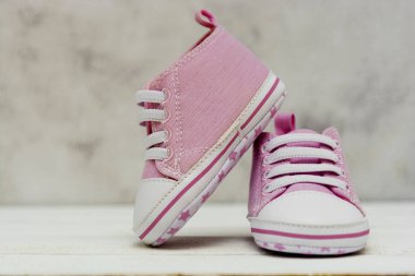 Pembe kız ayakkabıları, spor ayakkabıları, gri arka planda kapalı. Newbord, annelik, metin için fotokopi alanı ile hamilelik kavramı.