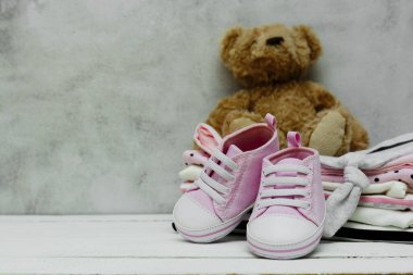 Pembe bebek ayakkabıları, yeni doğmuş kıyafetler ve yumuşak oyuncaklar. Annelik, eğitim ya da hamilelik kavramı ve metin için fotokopi alanı. Tebrik kartı.