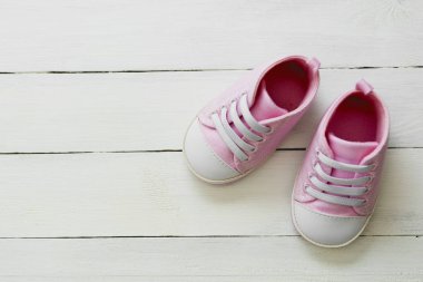 Gri arka planda pembe bebek ayakkabıları. Yeni doğan, annelik, metin için fotokopi alanı olan hamilelik kavramı.