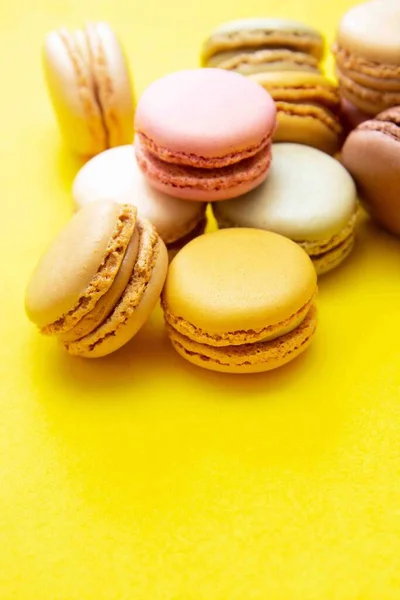 Colorful macaroons cookies, over yellow background. Traditional french dessert, abstract background.