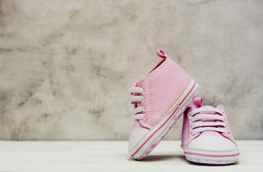 Pembe kız ayakkabıları, spor ayakkabıları, gri arka planda kapalı. Newbord, annelik, metin için fotokopi alanı ile hamilelik kavramı.