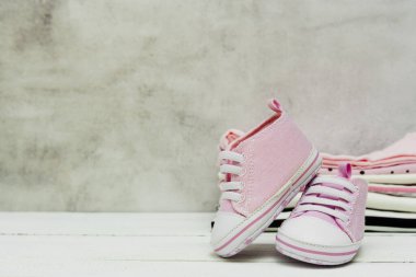 Pembe bebek ayakkabıları ve yeni doğan kıyafetleri. Annelik, eğitim ya da hamilelik kavramı ve metin için fotokopi alanı. Tebrik kartı.