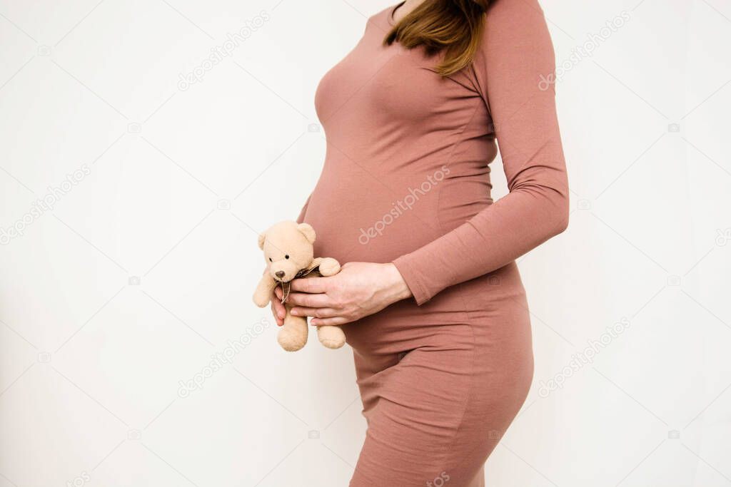 Beautiful pregnant woman with hands around her pregnant belly. Copy space. Motherhood concept.