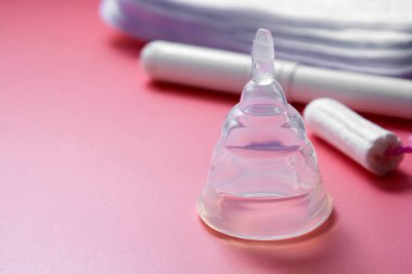 Adet bardağı ve pembe arka planda izole edilmiş kadın hijyen tamponu. Kopya alanı olan kadın hijyen ürünleri.