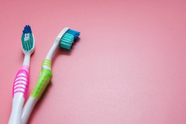 Pembe arka planda iki diş fırçası. Diş sağlığı hizmetleri, metin için kopyalama alanı.