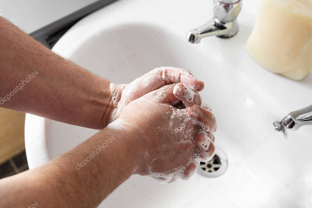 Close up of Man's hand wash his hands over sink in bathroom.