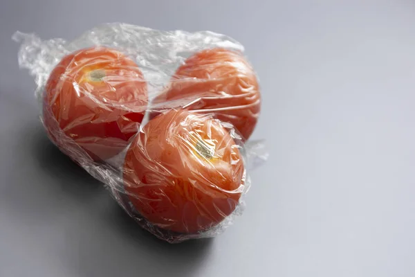 Wrapping plastic stretch film roll and fresh tomatoes abstract plastic waste concept.