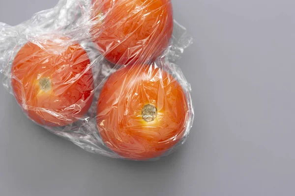 Wrapping plastic stretch film roll and fresh tomatoes abstract plastic waste concept.