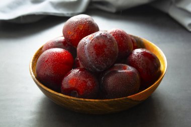 Satsuma kırmızı erikleri toplanır. Tahta tabakta lezzetli erikler.