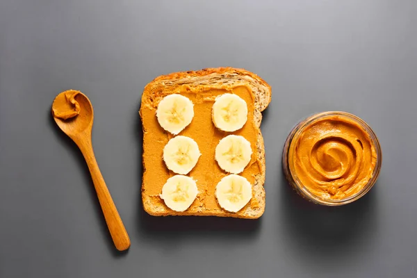Beurre d'arachide et pain grillé à la banane sur fond gris. Vue du dessus . — Photo