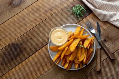 Soslu ve otlu kızarmış patates cipsi. Ahşap arkaplan, metin için kopyalama alanı.