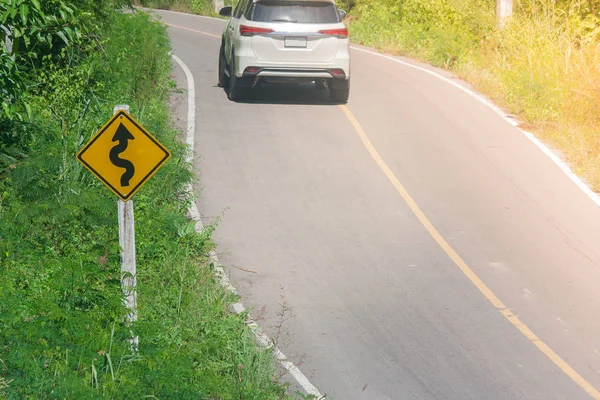 黄色の標識 迷路のトラフィック 車と日光の背景が付いている道の横にある緑のブッシュ — ストック写真