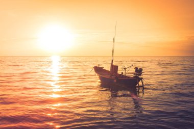 Güzel deniz manzarası içinde belgili tanımlık geçmiş günbatımı ışığı ile denizde yüzen balıkçı teknesi görüntüleyin. (Seçici odak)