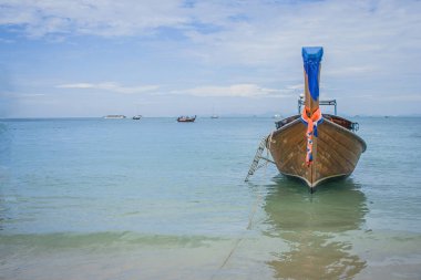 Geleneksel long tail tekne veya yolcu teknesi ile deniz manzarası ve mavi gökyüzü Krabi il, Tayland at arka planda Railay Beach üzerinde yüzen.