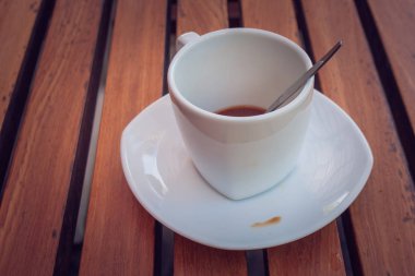 Kirli kahve fincanı ve vintage tarzı sabah içtikten sonra beyaz daire ve ahşap masa kaşık ayarı kapatın. (Yumuşak odak)