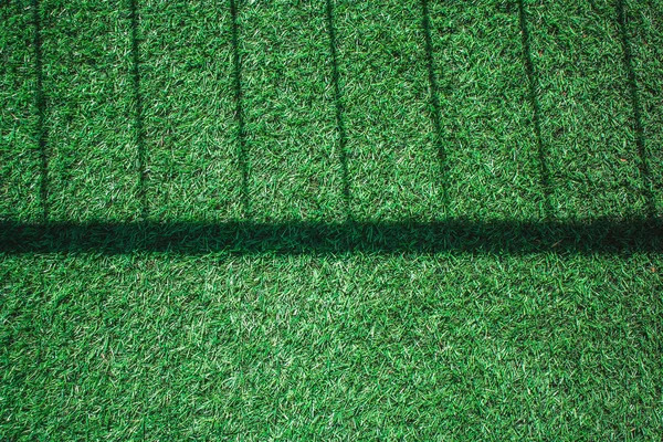 Top view close up  artificial grass or green grass texture with shadow of metal fence on grass in vintage style. (Soft focus)