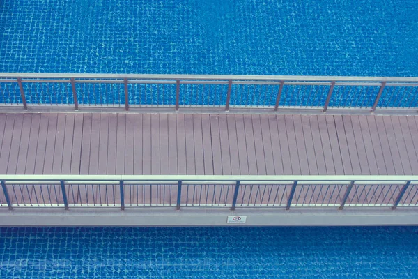 Top view of wooden walkway or footbridge over swimming pool at the resort.