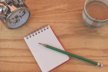 İş yaratıcı ve fikir kavramı: kullanılan yeşil kalem defter ile gümüş çalar saat ve kahve fincanı koymak ahşap masanın üzerine koy. (Seçici odak)