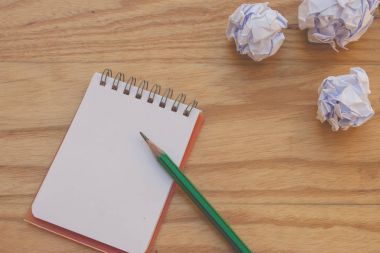 İş yaratıcı ve fikir kavramı: yeşil kalem koymak üstünde defter ahşap masanın üstüne koy beyaz buruşuk kağıt topu ile kullanılır. (Seçici odak)