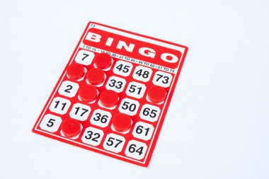 İş kavramı: Kırmızı çip beyaz arka plan üzerinde izole kırmızı bingo kartı. (Seçici odak)