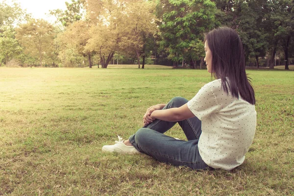 リラックスした女性とビンテージ スタイルの公園で緑の草の上にあります — ストック写真