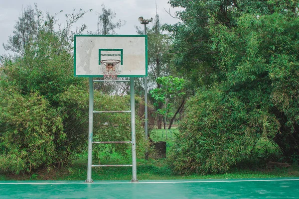 Old outdoor basketball court in the park with green natural in the background. (Selective focus)