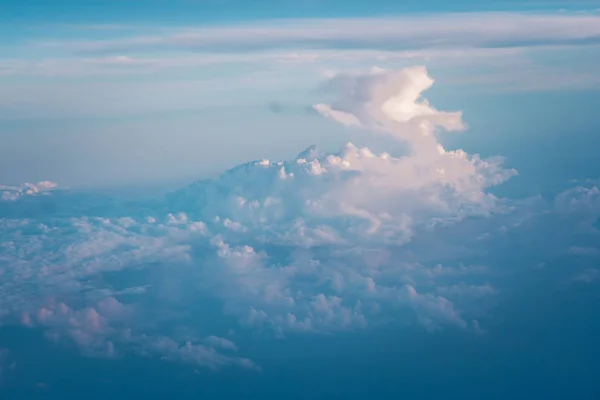 Clouds and blue sky view out from window of airplane fying over earth ground. (Selective focus)