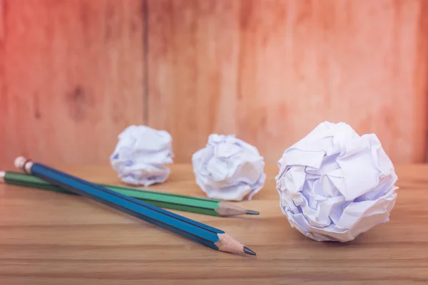 Business Creative and Idea Concept : Used pencils with many white crumpled paper ball put on wooden floor in vintage style. (Selective focus)