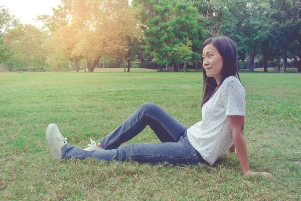座って 横になっている美しいアジアの女性は 公園の緑の草の草原フィールドでリラックスします 彼女の幸せを感じながら リフレッシュ — ストック写真