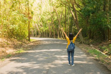 Yalnız kadın Gezgin veya yeşil ağaçlar arasında contryside yol boyunca yürüyüş backpacker, o kaldırsın baş ve duygu mutluluk üzerinde.