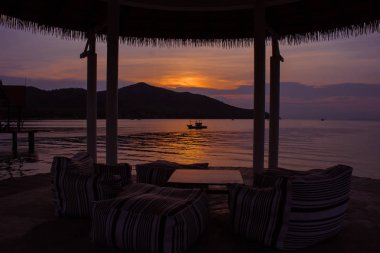 Güzel deniz manzarası görünümünü alacakaranlık zaman arka planda günbatımı ışığı ile denizde yüzen balıkçı teknesi. (Seçici odak)