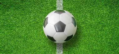 Futbol topunun ya da futbolun yeşil suni çimen futbol sahasının ortasındaki üst görünümü.
