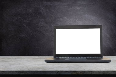 Beton masa üzerinde beyaz ekran ve arka planda karatahta olan siyah dizüstü bilgisayar kullanıldı.