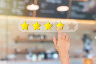 Müşteri Geribildirim Konsepti: Arka plandaki cafe restoranının veya kahve dükkanının ön görüntüsünün bulanık olduğu en iyi servis sıralamasını vermek için bir sarı yıldıza elle basmak.