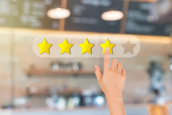 Customer Feedback Concept : Hand pressing one yellow star for giving best service ranking with blurred image of front view of cafe restaurant or coffee shop in background.