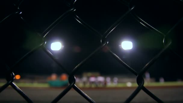 Dolly detrás de una cerca viendo un equipo de fútbol de la escuela secundaria — Vídeo de stock