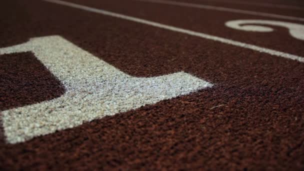 Muñeca lenta de un número 1 en una pista de atletismo — Vídeos de Stock