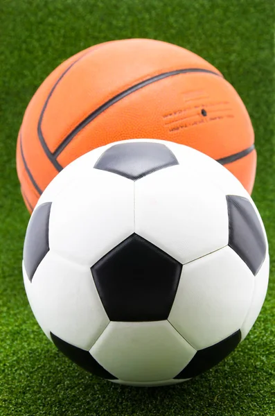 Pallone da calcio con pallacanestro su sfondo verde erba — Foto Stock