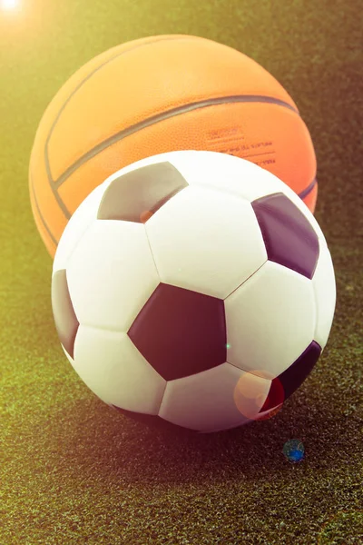 Pallone da calcio con pallacanestro su sfondo verde erba — Foto Stock