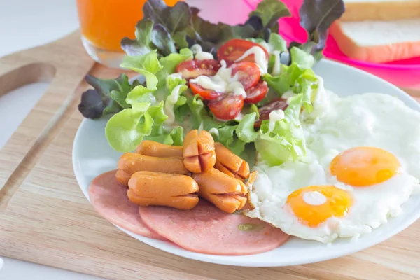 Petit déjeuner avec œufs frits, bacon, saucisses, toasts et salade fraîche — Photo