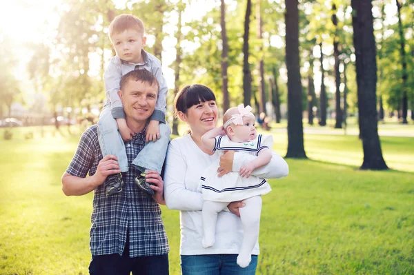 Mladá rodina se dvěma dětmi v letní park — Stock fotografie
