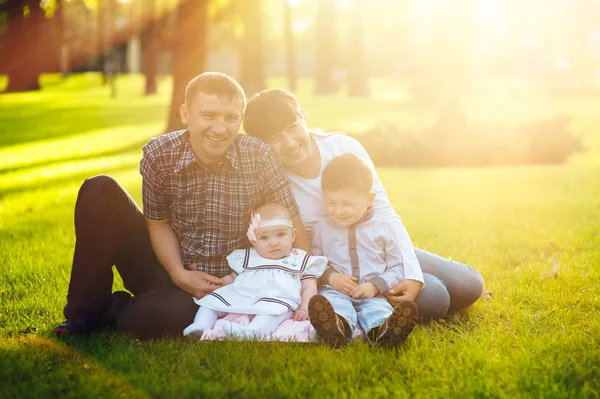 Mladá rodina se dvěma dětmi v letní park — Stock fotografie