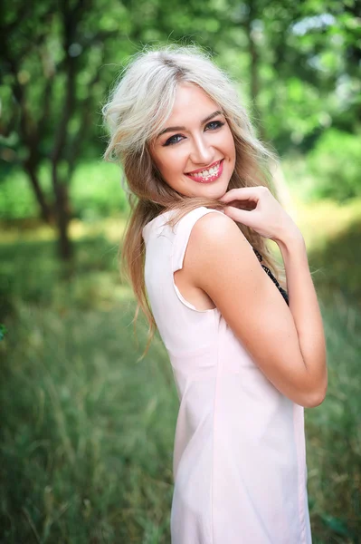Женщина с длинными светлыми волосами позирует в летнем парке — стоковое фото