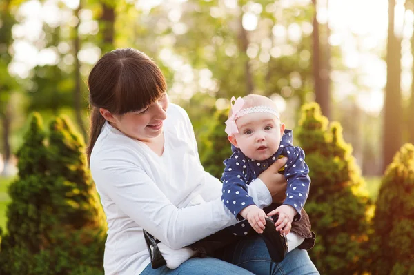 Young mother carrying a baby girl and walks in the park — Stock Photo, Image