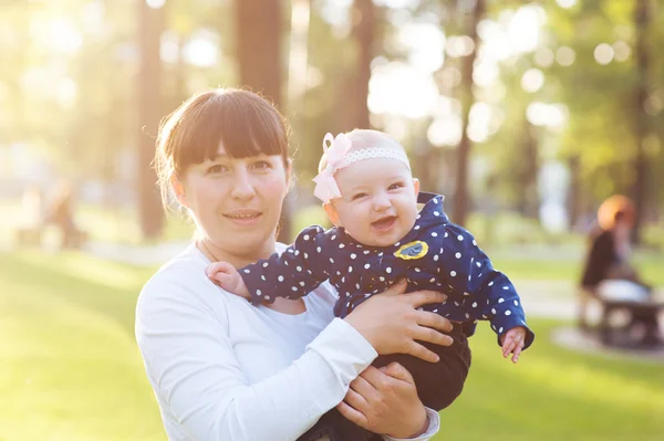 Young mother carrying a baby girl and walks in the park — Stock Photo, Image