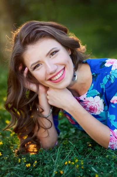 Relaxado bela jovem mulher em vestido azul deitado na grama — Fotografia de Stock