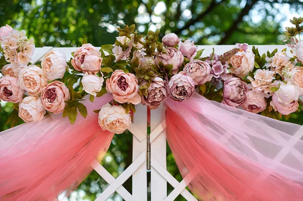 Hermoso arco de boda blanco decorado con flores de color rosa y rojo al aire libre —  Fotos de Stock