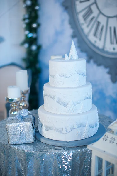 Tří vrstvou bílé holiday dort na stůl zdobený jedle a dárkové krabičky — Stock fotografie